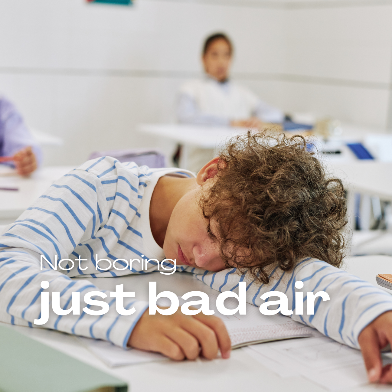 Student resting head on desk in classroom, demonstrating poor air quality effects