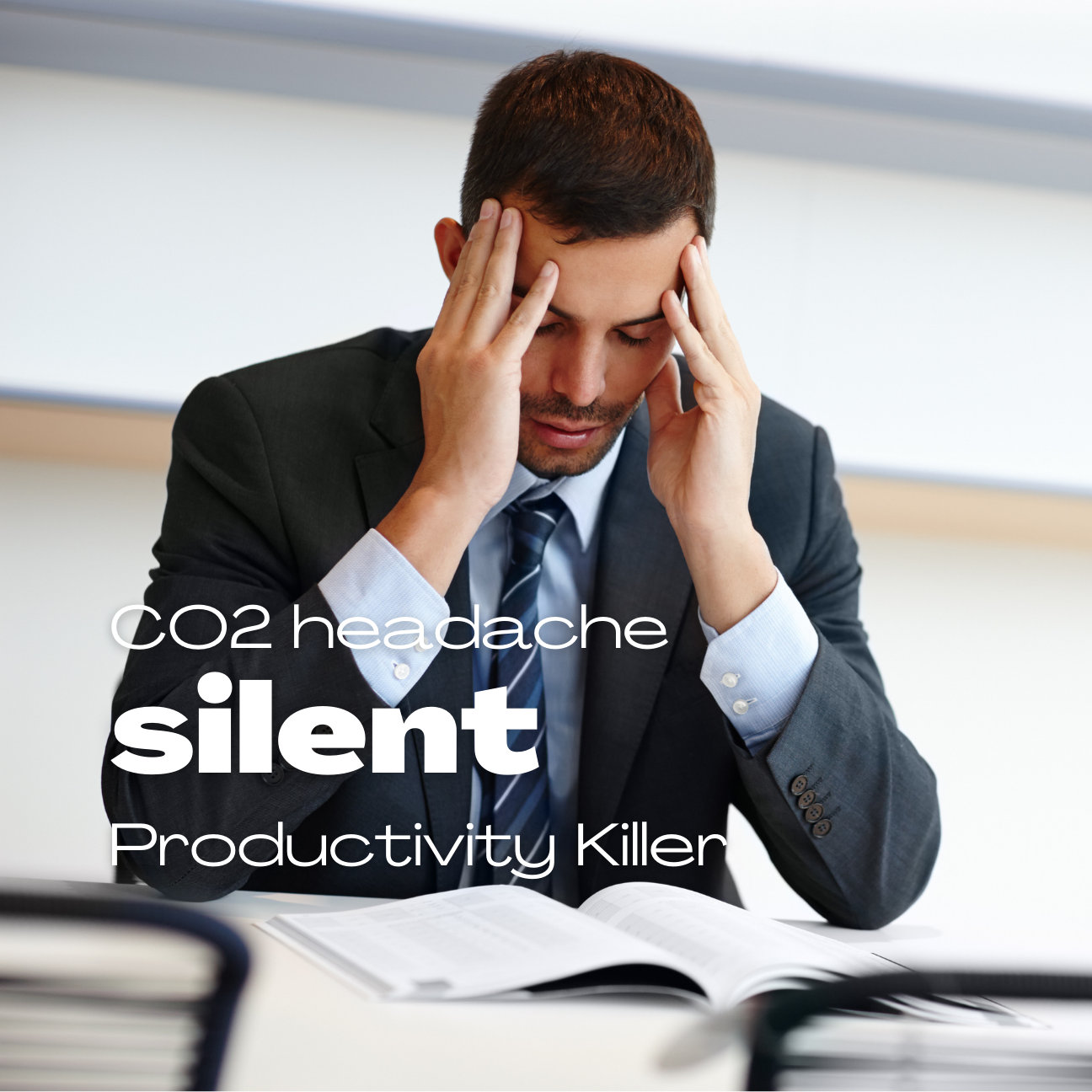 Professional at desk holding temples showing signs of CO2-induced headache